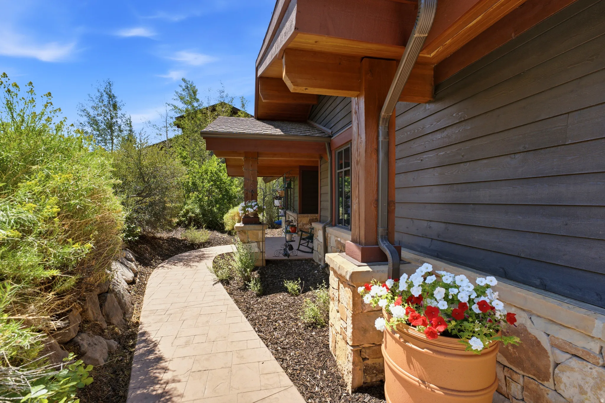 Stonework exterior featuring a covered porch, wood-tone columns, and dark siding