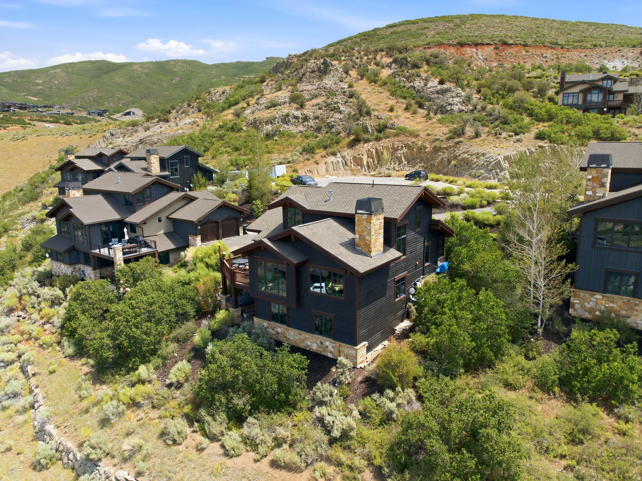 Hillside residence with dark siding, stone accents, and multiple dormer windows