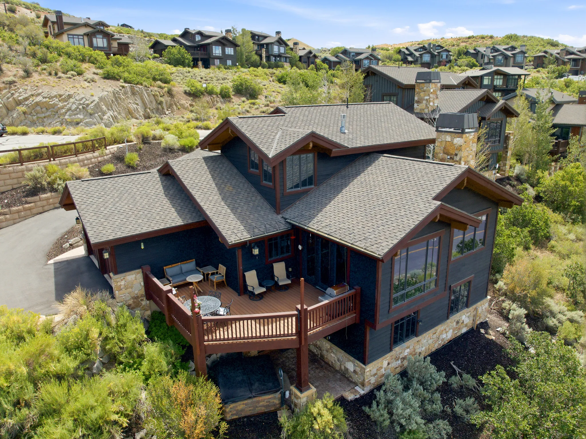 Multi-level residential structure featuring dark siding, stone accents, and a prominent outdoor deck