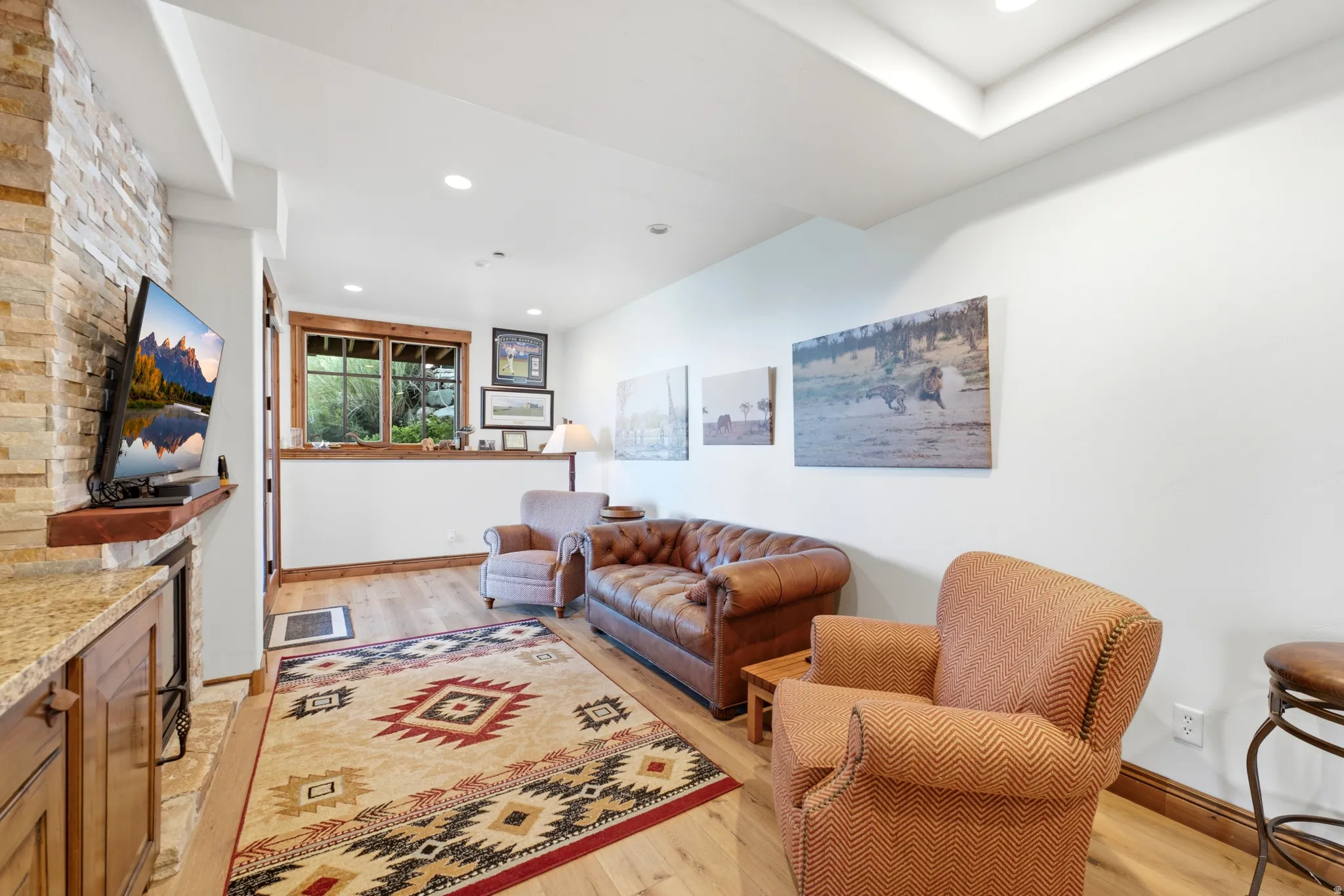 Living area featuring wood-finish flooring, a stacked stone wall accent, and recessed lighting