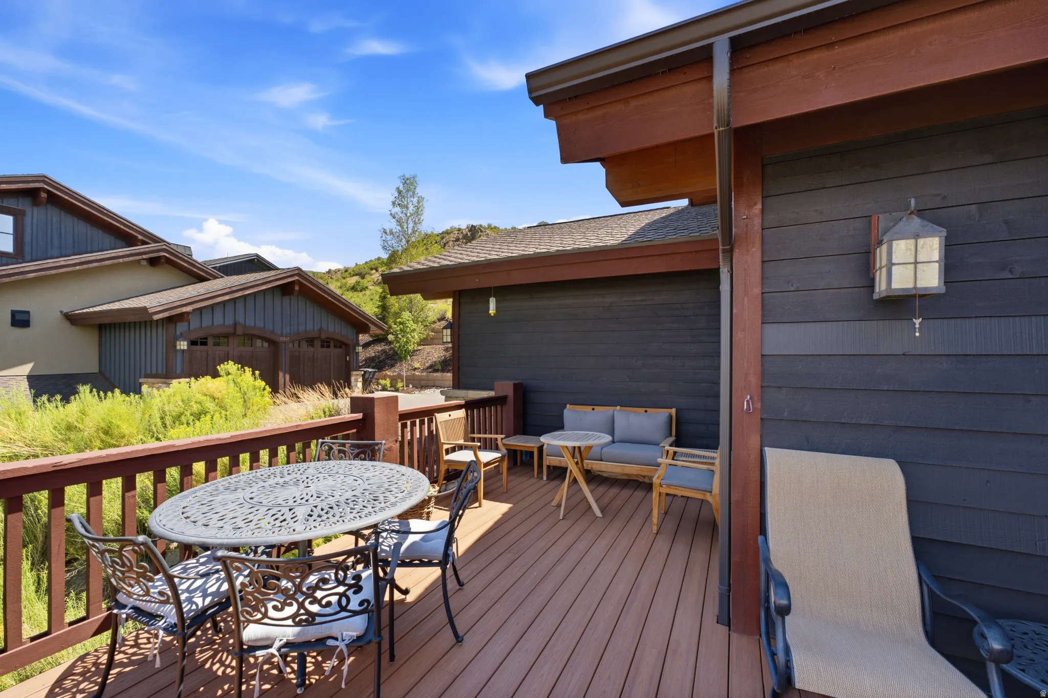 Spacious outdoor deck featuring wood-finish flooring, a sturdy railing, and an exterior wall light fixture