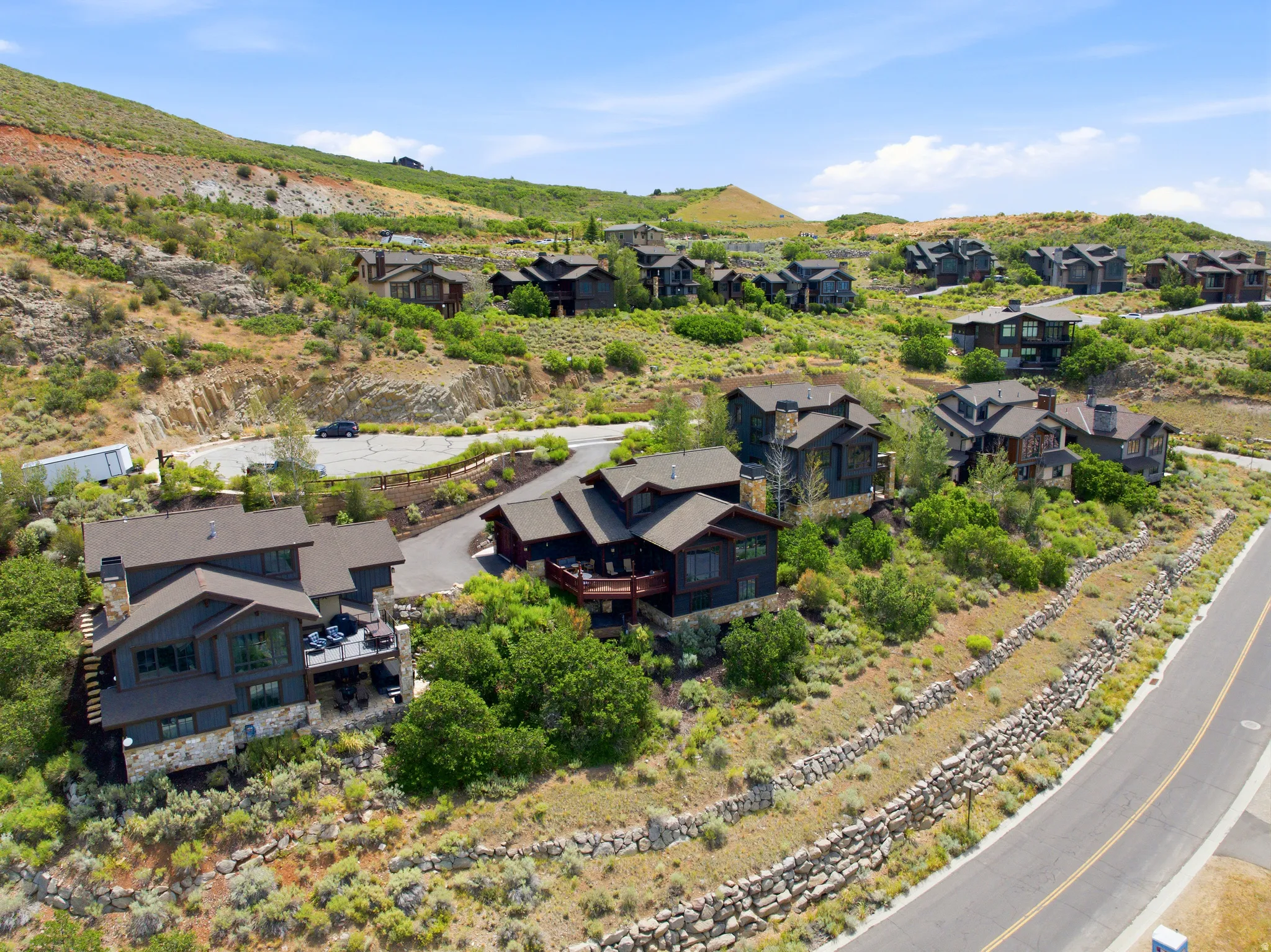 Hillside community featuring multiple residences with dark siding and stone accents