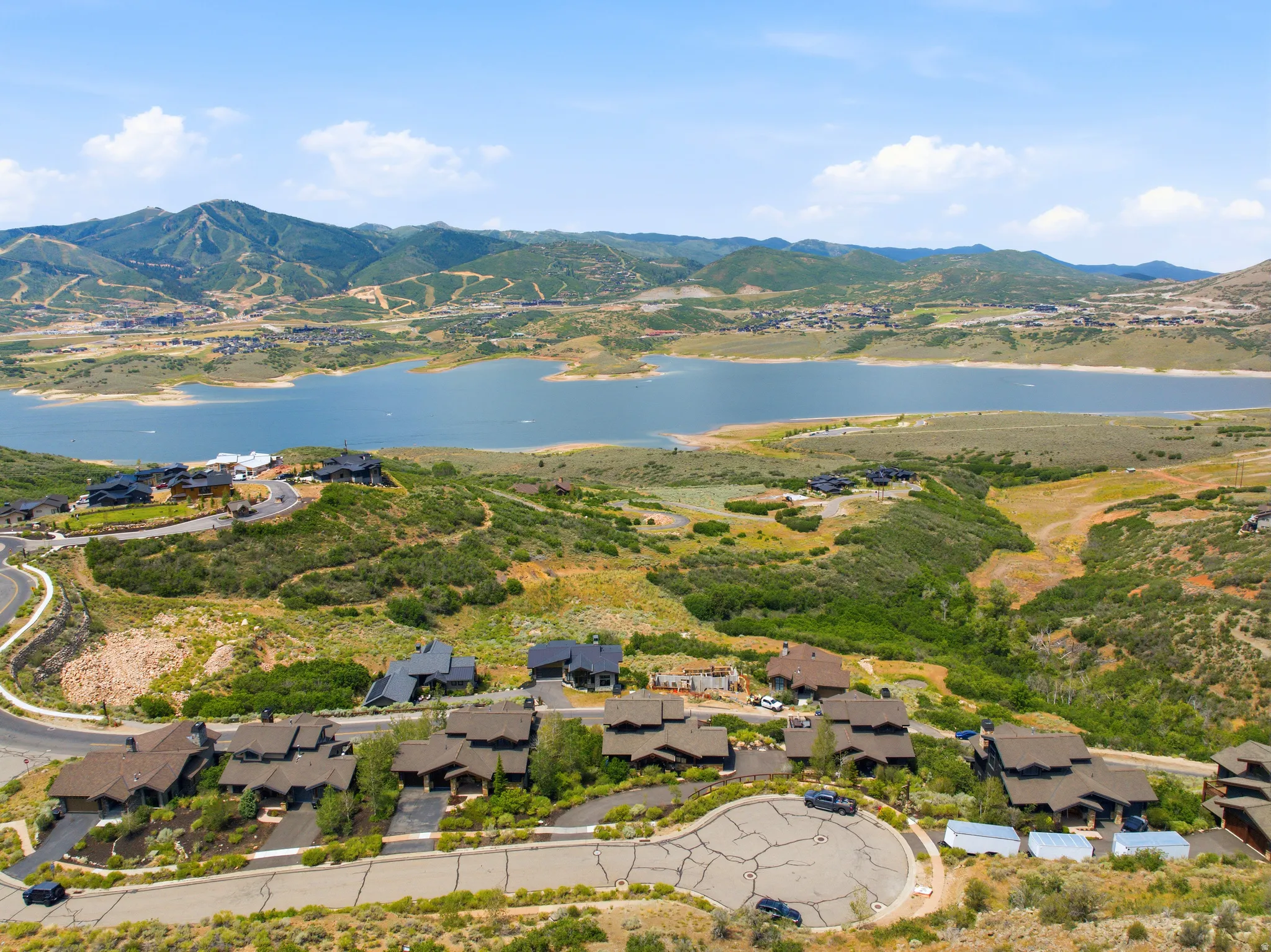 Aerial perspective showcasing a residential area with a lake and mountains in the background