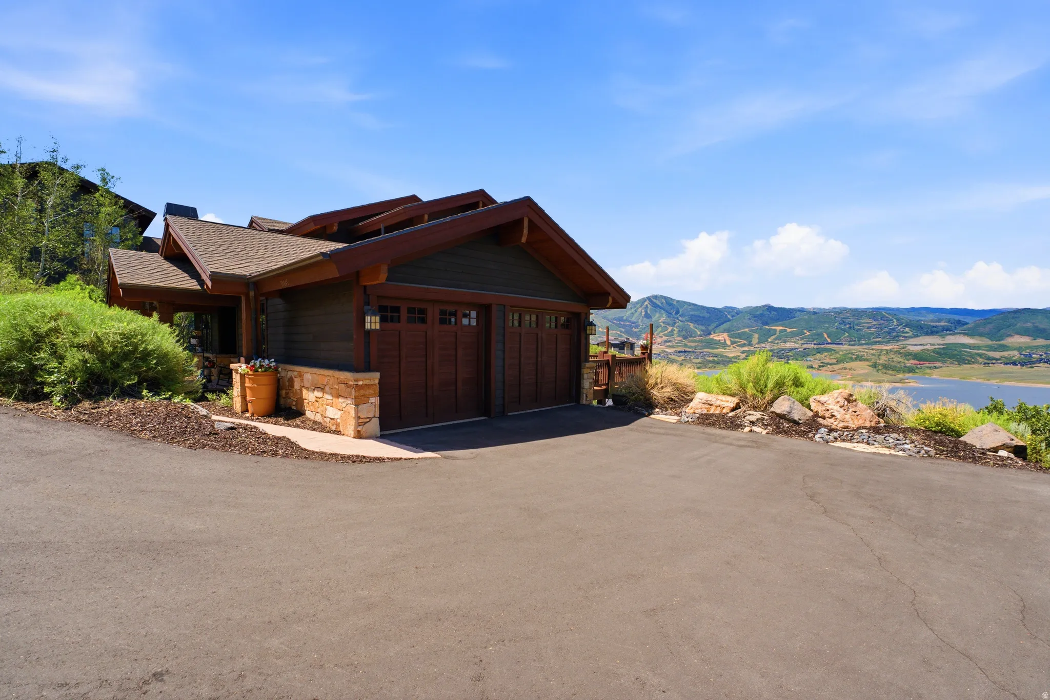 Craftsman-style exterior featuring dark wood siding, a multi-gabled roofline, and an integrated two-car garage with wood-paneled doors