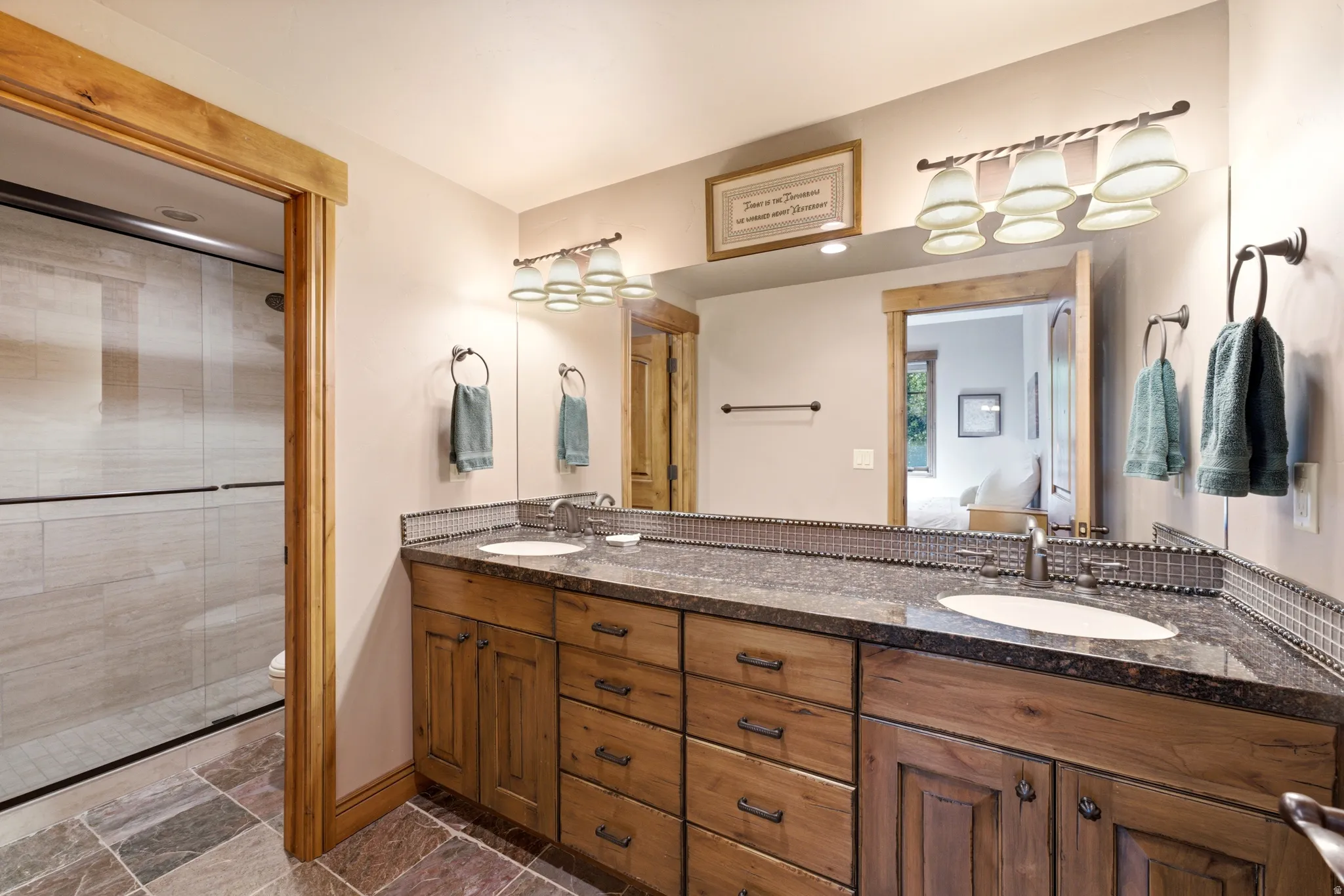 Guest Room Ensuite Double vanity featuring wood cabinetry, undermount sinks, and granite countertops with a mosaic tile backsplash