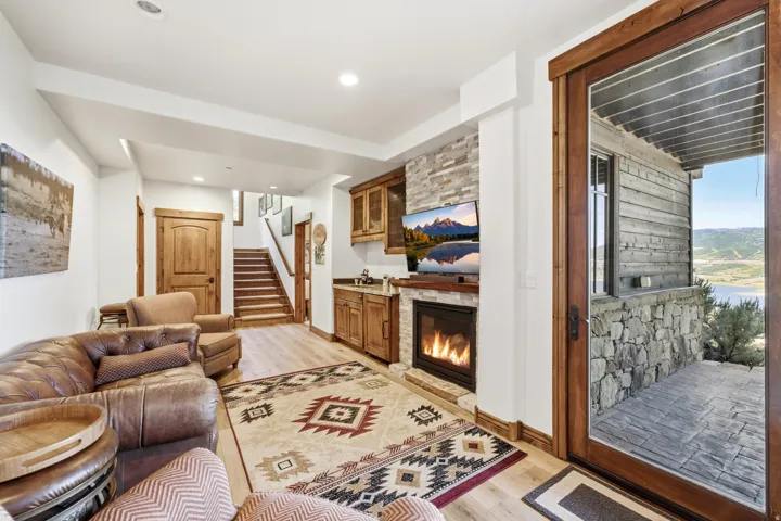 Living area featuring a stone accent wall with a built-in fireplace, wood-finish flooring, recessed lighting, and a wet bar with wood cabinetry and a countertop