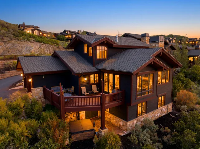 Multi-level residence featuring dark siding, stone accents, and a shingle roof