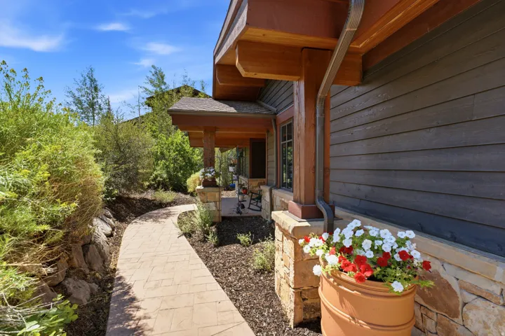 Stonework exterior featuring a covered porch, wood-tone columns, and dark siding