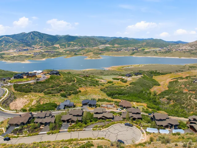 Aerial perspective showcasing a residential area with a lake and mountains in the background