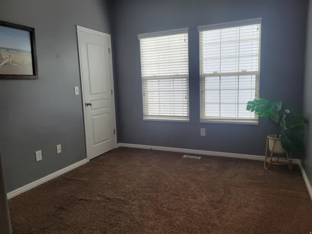 Room featuring two windows with horizontal blinds, gray walls, and brown carpet flooring