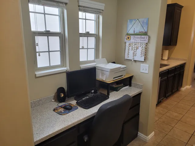 Dedicated workspace featuring built-in cabinetry, dual windows with blinds, and a speckled countertop