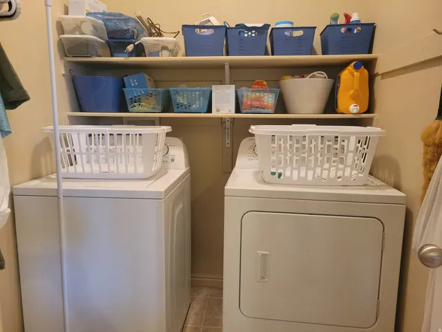 Dedicated laundry area featuring a washer and dryer, complemented by two integrated storage shelves and durable vinyl flooring
