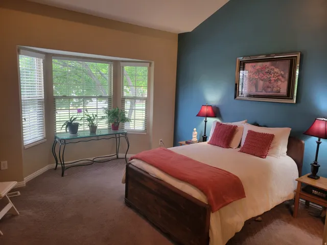 Bedroom featuring a bay window, vaulted ceiling, and carpeted flooring