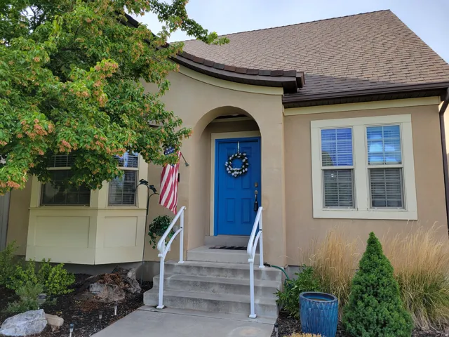 Stucco exterior featuring a bright blue entry door, an arched entryway, and a brown shingle roof