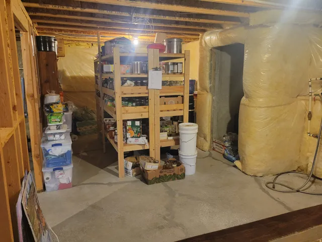 Unfinished basement space featuring exposed wooden framing, concrete flooring, and visible insulation