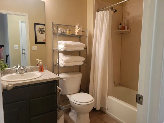 Bathroom featuring a dark wood-finish vanity with a light speckled countertop, an integrated sink, and a large wall mirror