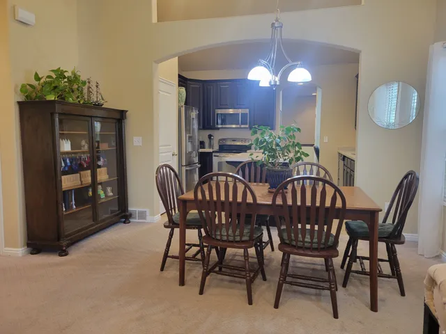 Dining area featuring an arched entryway, recessed ceiling details, and a chandelier with frosted glass shades