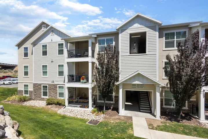 Multi-story residential building featuring light-colored siding and stone veneer accents