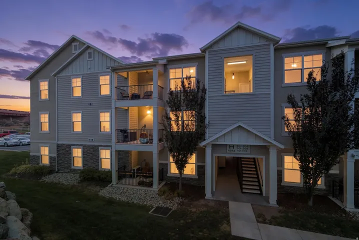 Multi-story residential building featuring horizontal siding, stone veneer accents, and multiple private balconies