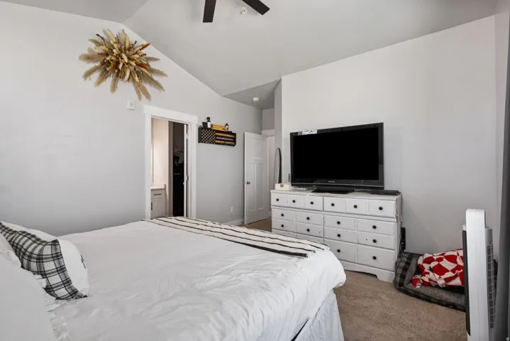 Carpeted bedroom featuring vaulted ceilings and a ceiling fan