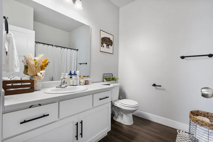 Modern bathroom featuring a white vanity with black hardware, an integrated sink, and wood-finish flooring
