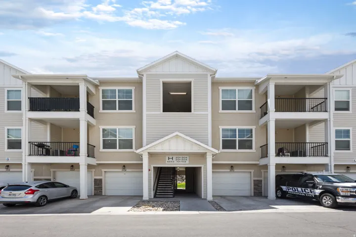 Multi-story residential building with light-colored siding and stucco accents