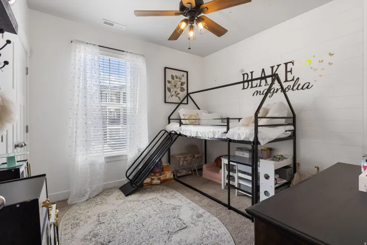 Bedroom featuring a window with blinds, a ceiling fan with integrated lighting, and carpet flooring