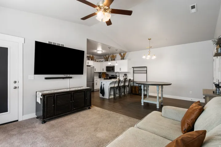 Open-concept living area with vaulted ceilings and wood-finish flooring extending into the kitchen