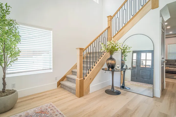 Entryway featuring a grand staircase with light wood newel posts and black wrought iron balusters