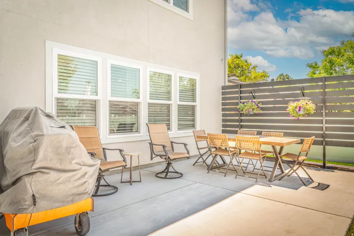 Spacious concrete patio featuring a horizontal slat privacy fence, white-framed windows with blinds, and a light-colored stucco exterior