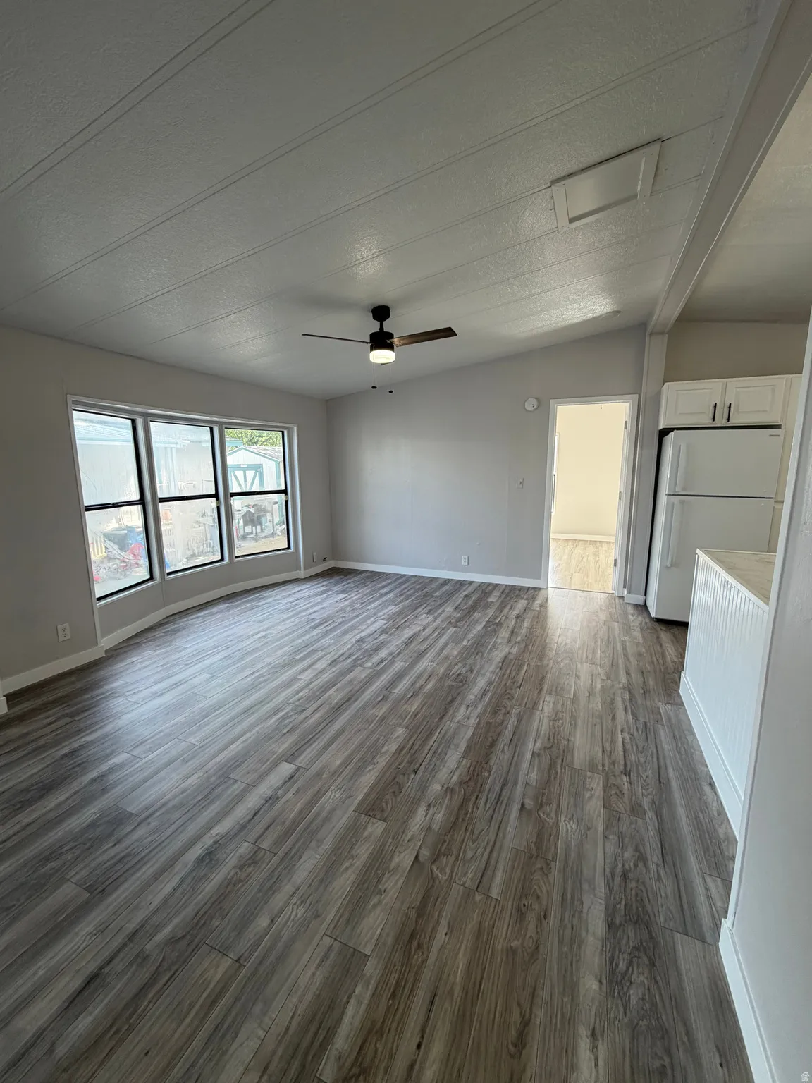 Open concept living space featuring wood-finish flooring, a vaulted ceiling, and ample natural light from multiple windows