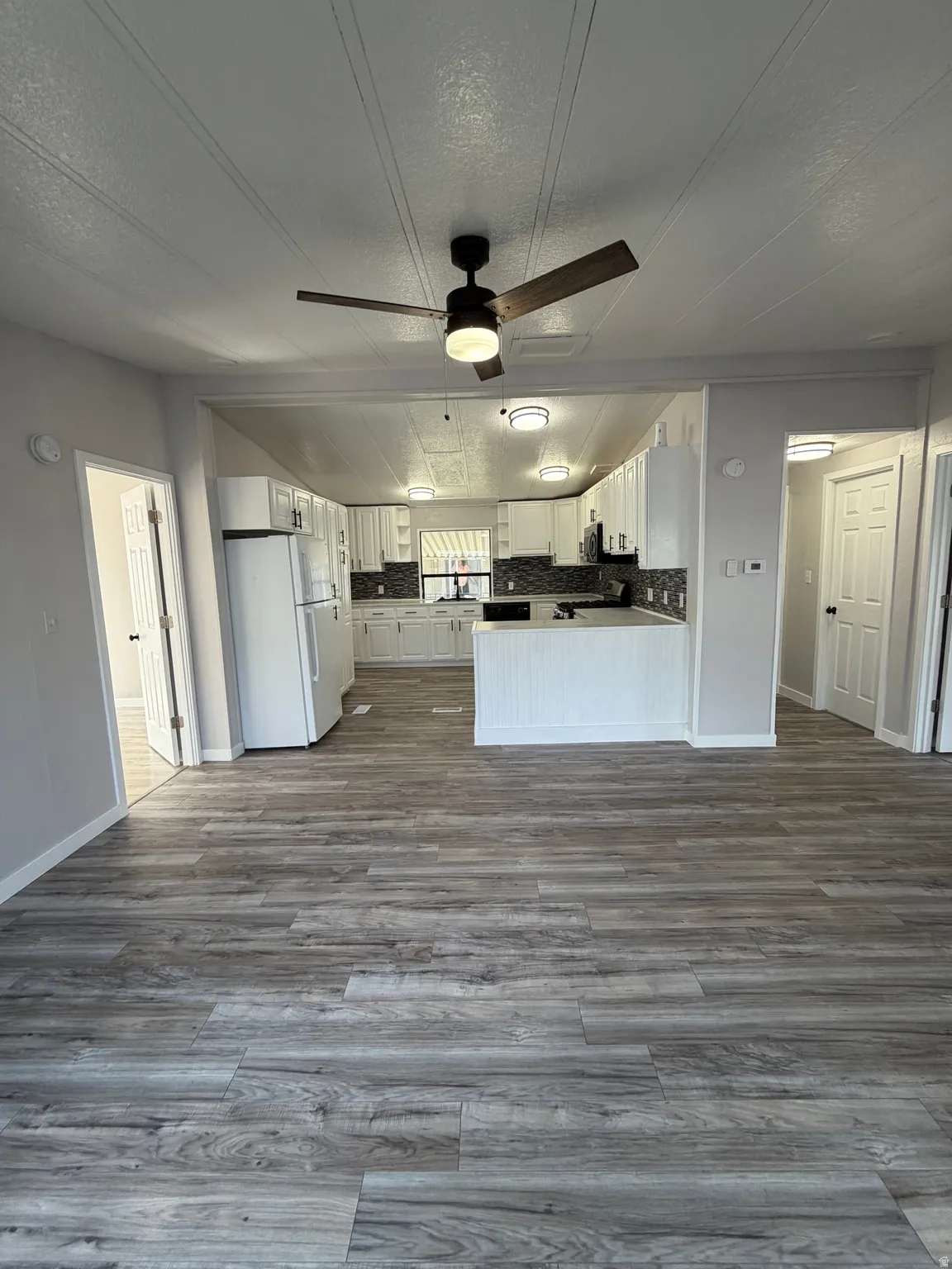 Open-concept living space featuring wood-finish flooring, a contemporary ceiling fan, and recessed lighting