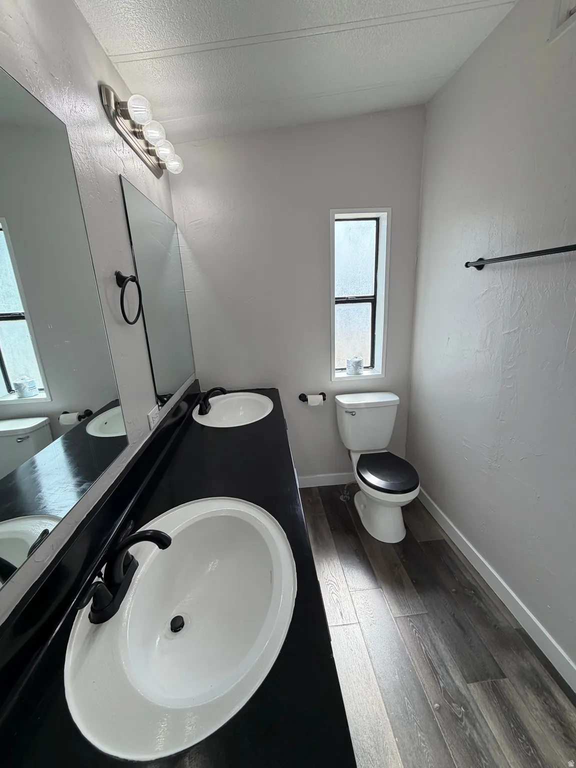 Dual white oval sinks set into a dark countertop, complemented by dark-finish faucets