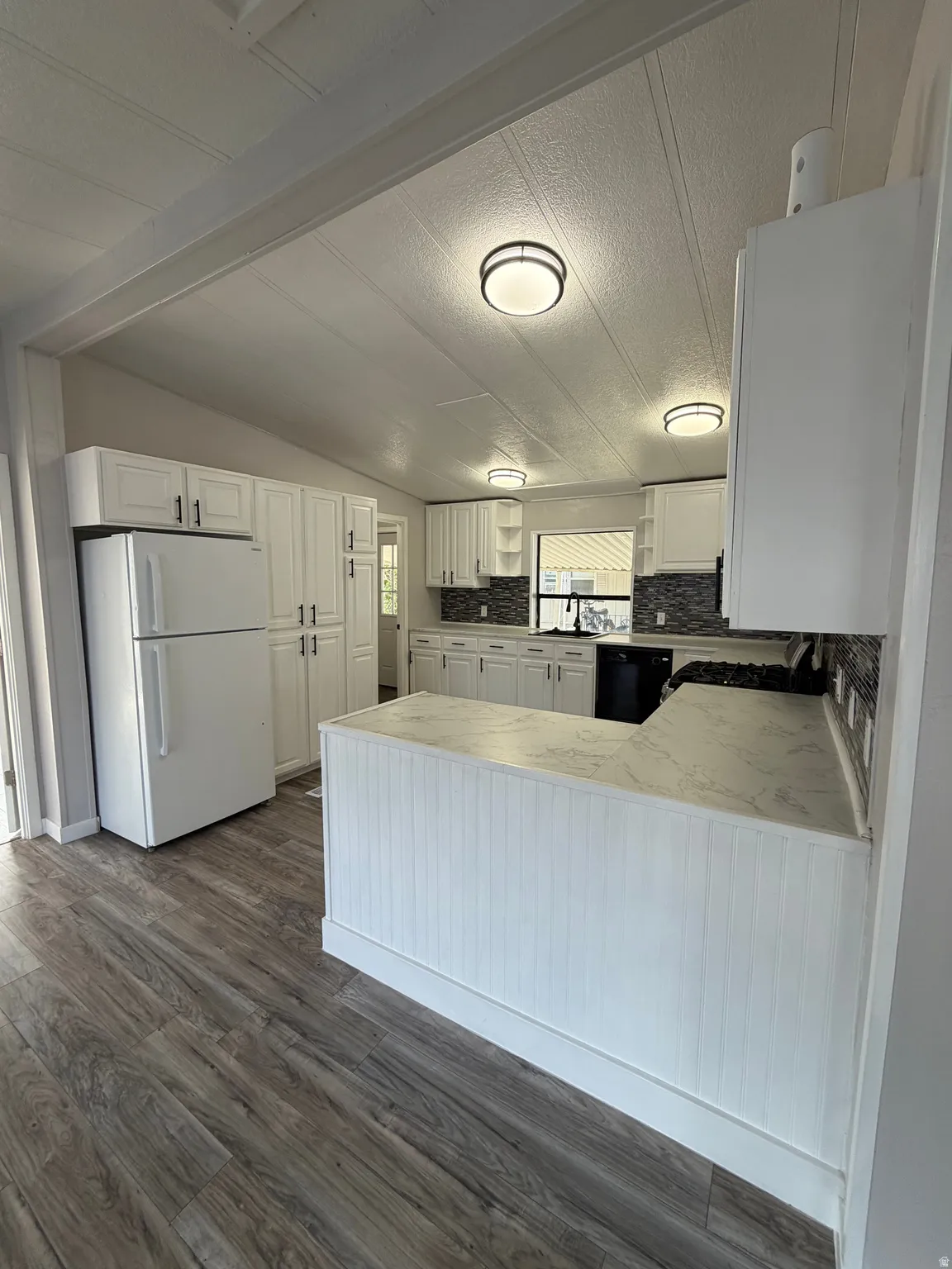 Modern kitchen featuring white cabinetry, stone-finish countertops, and a mosaic tile backsplash
