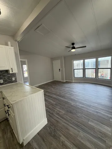 Open-concept living area featuring wood-finish flooring, a contemporary ceiling fan, and a light gray wall palette