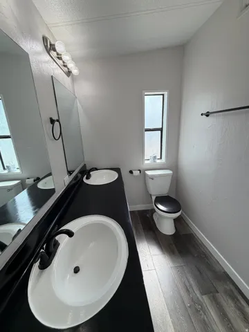 Dual white oval sinks set into a dark countertop, complemented by dark-finish faucets