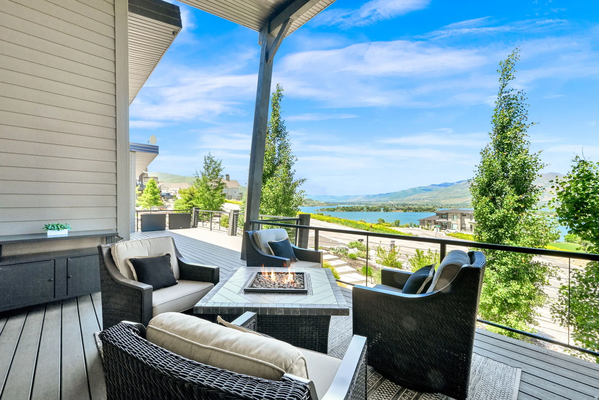 Spacious covered deck featuring composite decking, a built-in fire pit, and glass panel railings