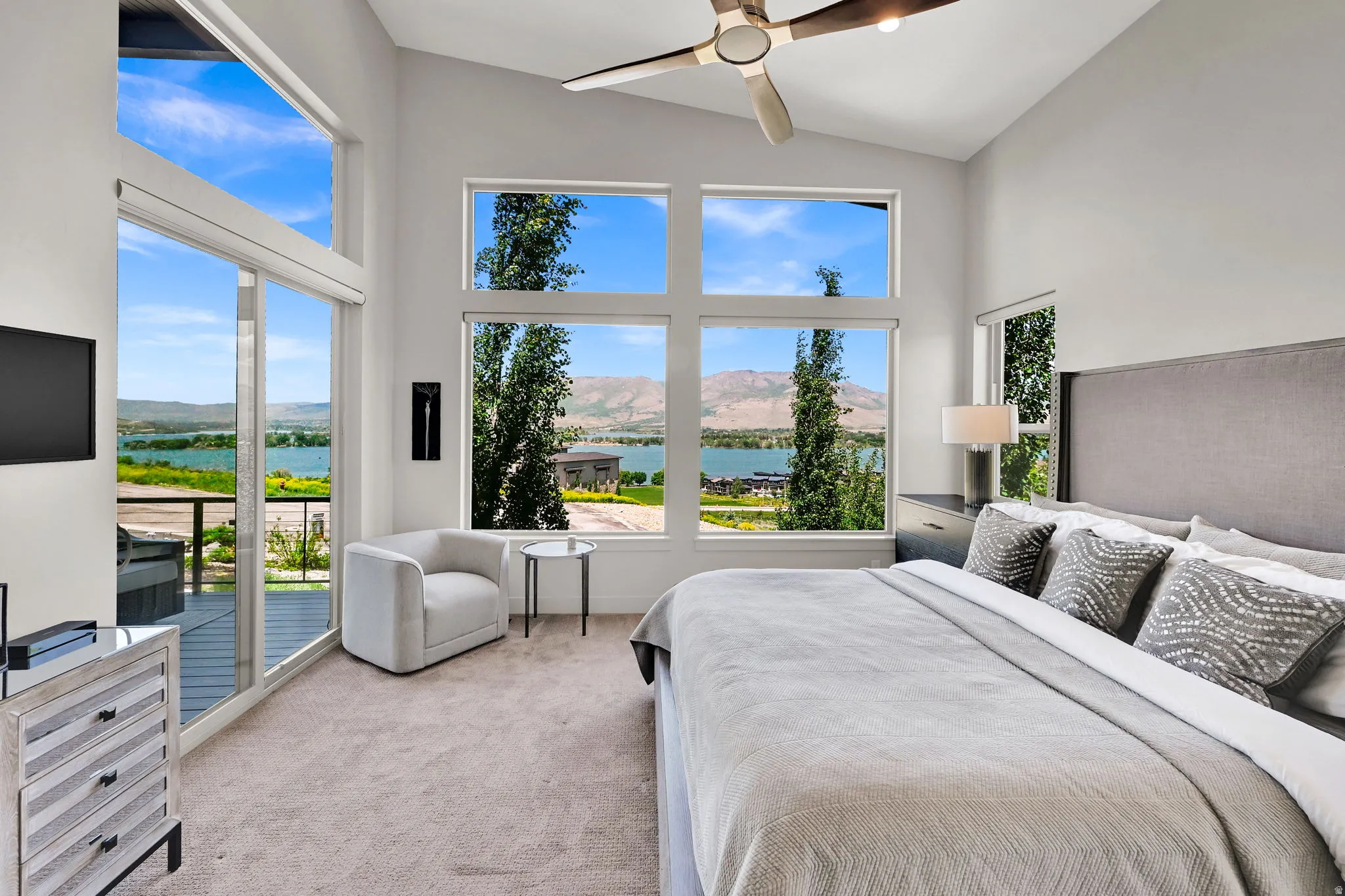 Vaulted ceiling bedroom featuring panoramic windows, glass sliding doors to an exterior balcony, and a multi-pane window configuration