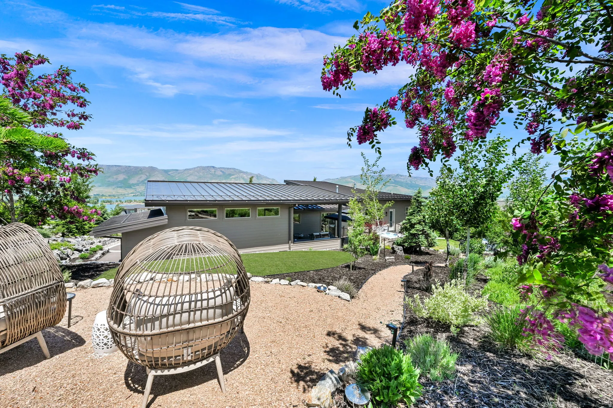 Expansive exterior featuring a gravel pathway, diverse plantings, and a manicured lawn