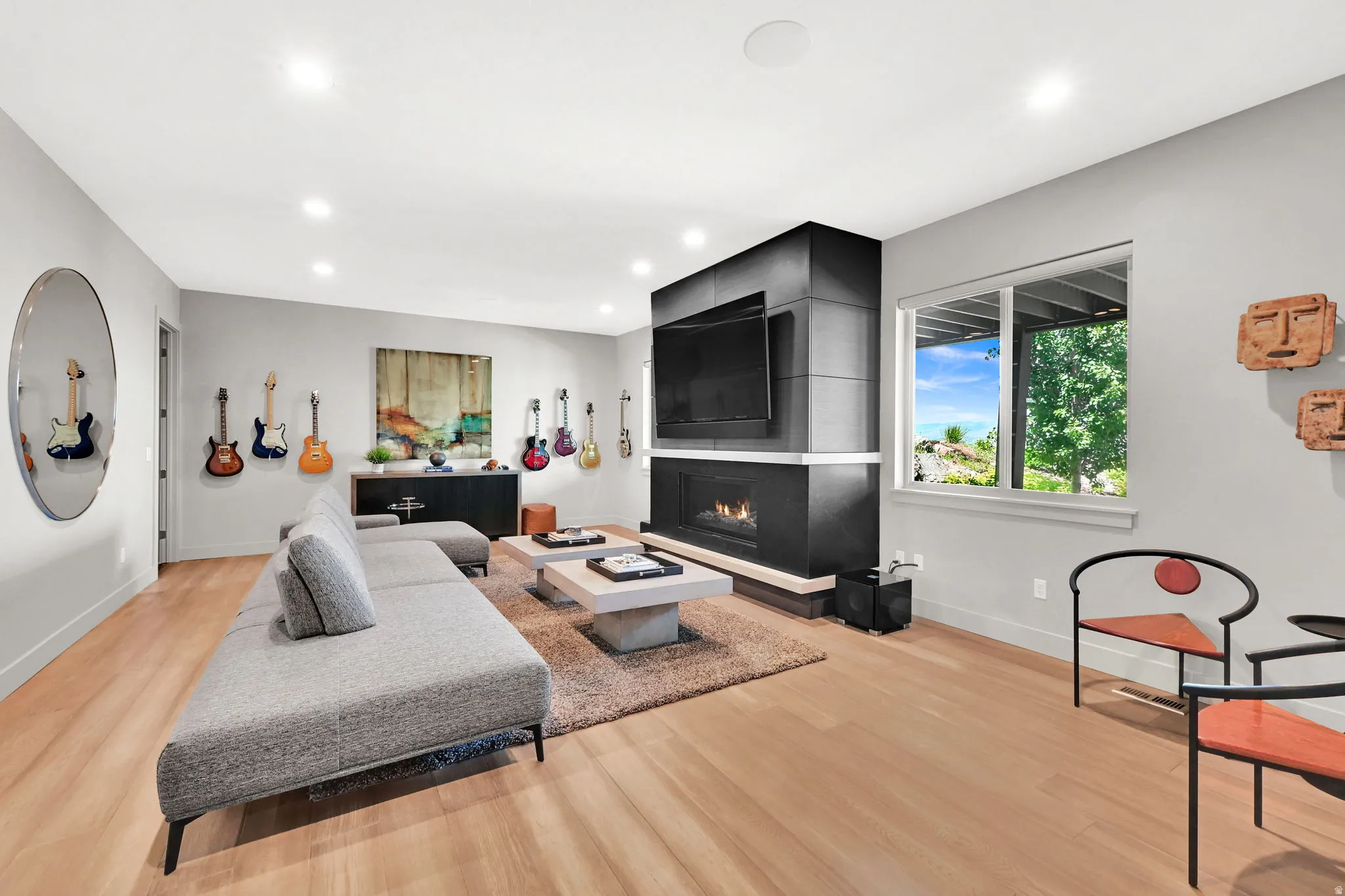 Open-concept living space featuring light wood-finish flooring, recessed ceiling lighting, and a contemporary fireplace with a mounted television