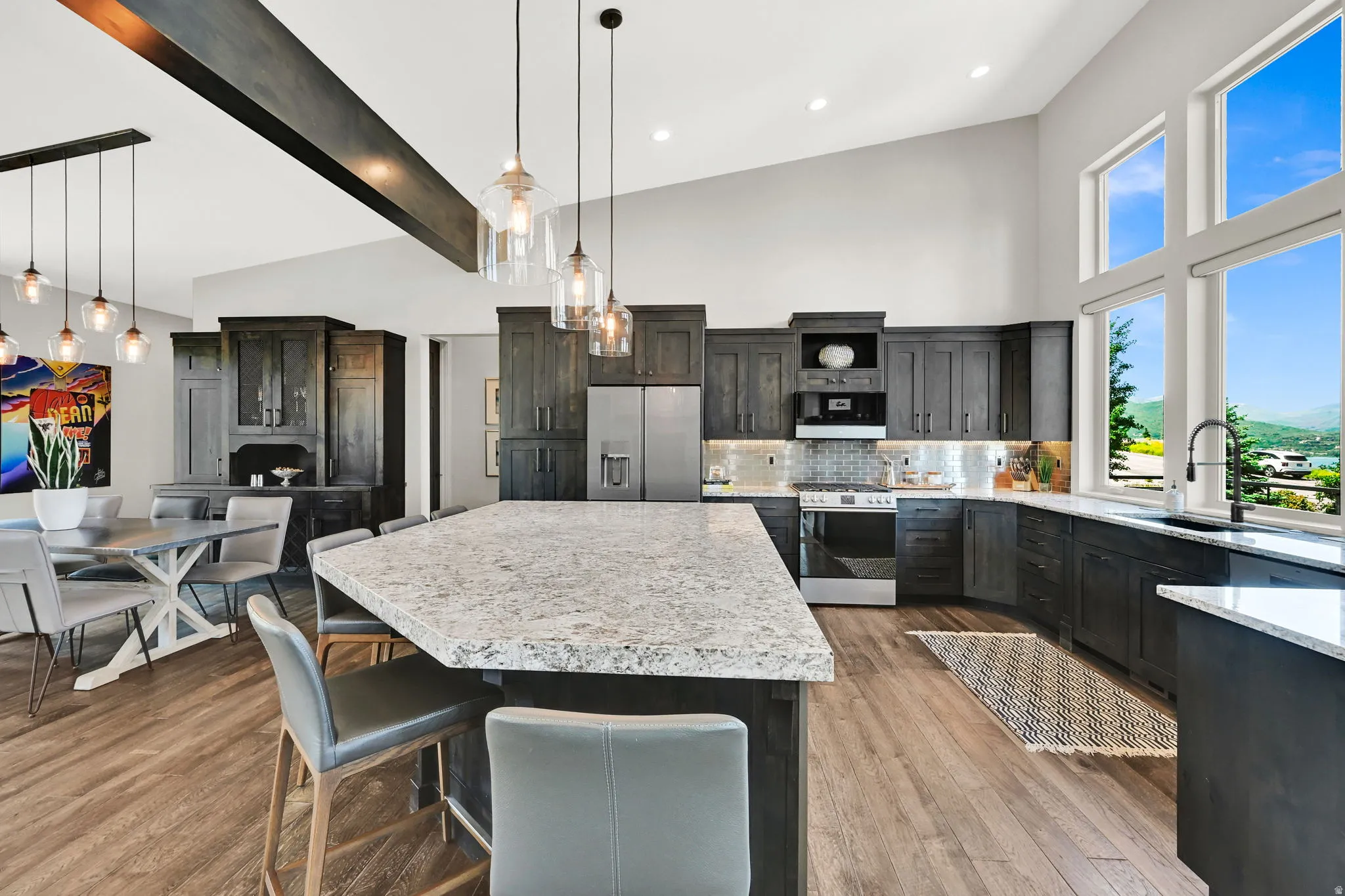 Open-concept kitchen featuring wood-finish flooring, dark wood cabinetry, a large kitchen island with a light-colored countertop, and a stainless steel refrigerator