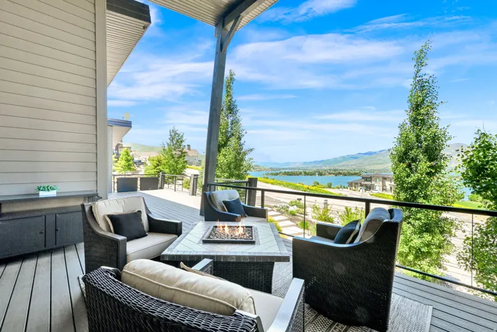 Spacious covered deck featuring composite decking, a built-in fire pit, and glass panel railings