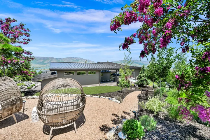 Expansive exterior featuring a gravel pathway, diverse plantings, and a manicured lawn