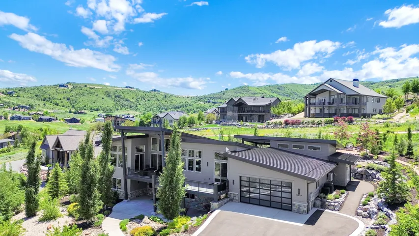 Contemporary hillside residence with multiple balconies, a glass-paneled garage door, and a low-slope roofline