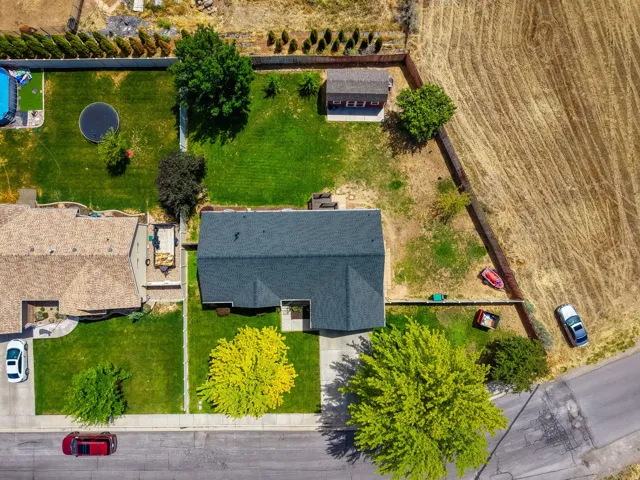 Aerial perspective showcasing a property an expansive green lawn, mature trees, and a detached shed