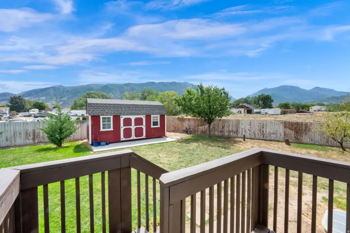 Expansive backyard featuring a red storage shed, vibrant green lawn, mature trees, and a wooden privacy fence