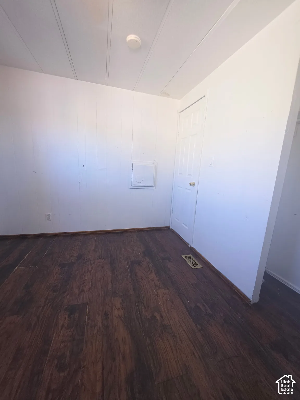 Dark wood-finish flooring with white paneled walls and a white ceiling