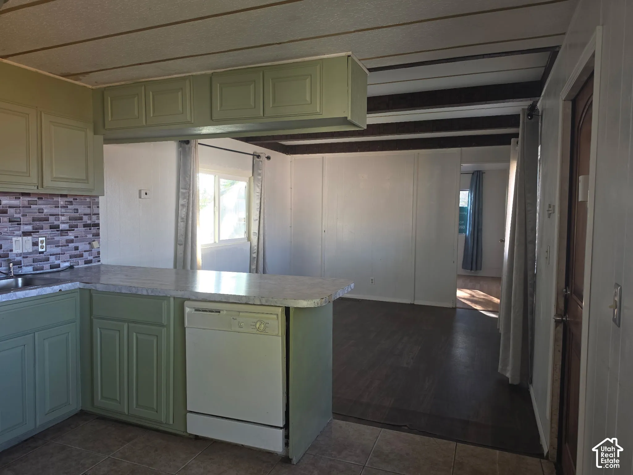 Kitchen featuring sage green cabinetry, a mosaic tile backsplash, and a built-in dishwasher