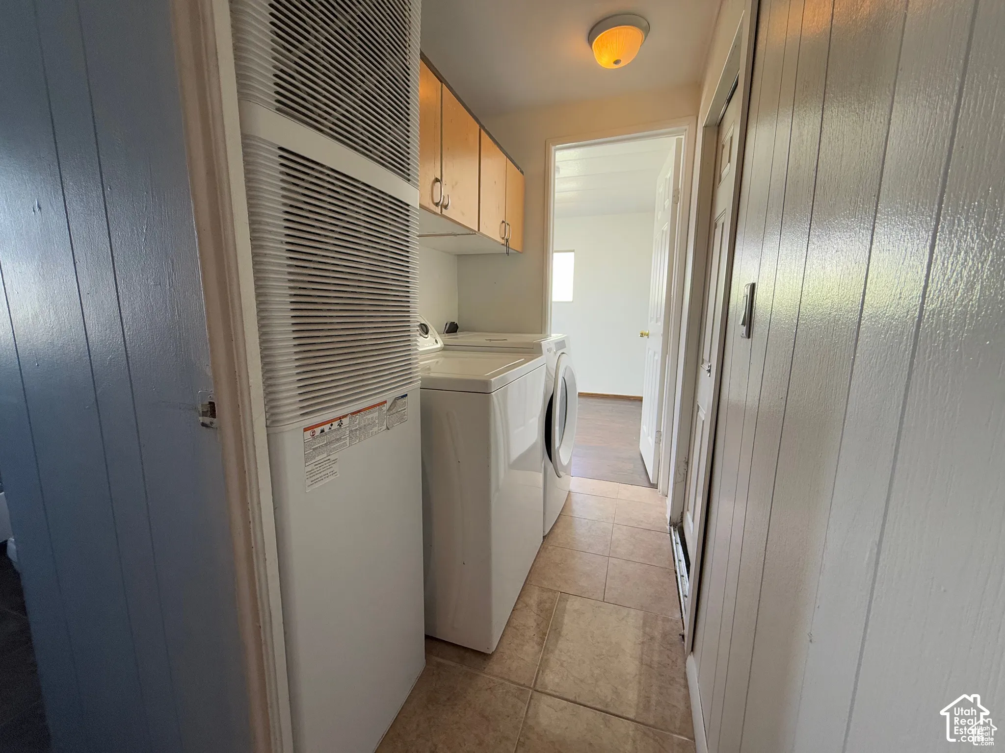 Dedicated laundry area featuring ceramic tile flooring, wood cabinetry, and overhead lighting