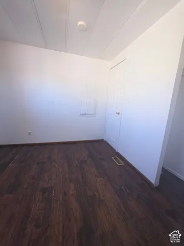 Dark wood-finish flooring with white paneled walls and a white ceiling